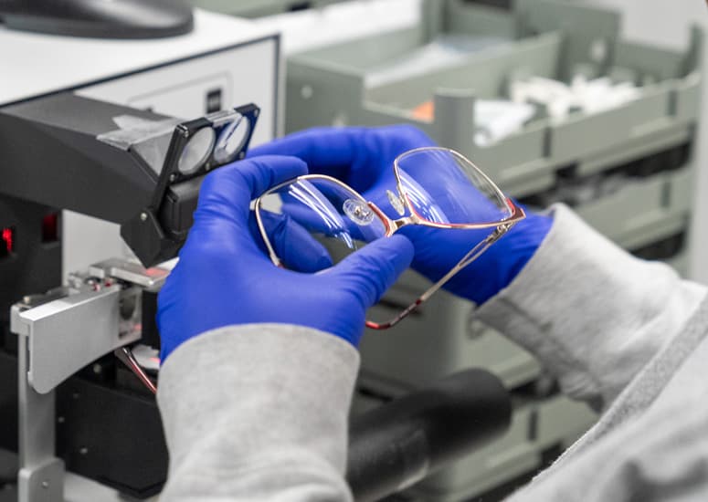 A lab technician inspecting a finished pair of glasses