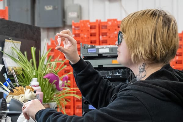 A technician holding up a lens to inspect it