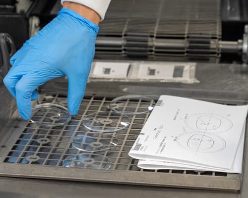 Surfaced lenses on a lab tray beside their job ticket
